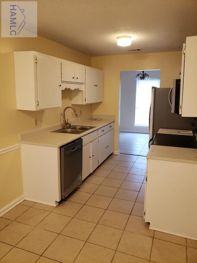 kitchen featuring appliances with stainless steel finishes, a textured ceiling, sink, light tile patterned floors, and white cabinetry