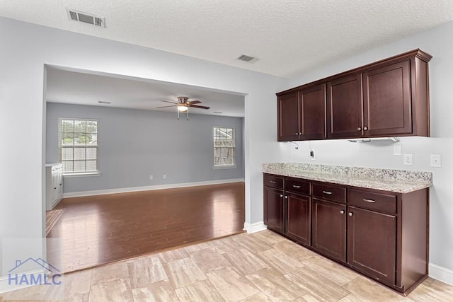 42 Kinlock Ct, Midway, GA 31320 - kitchen with ceiling fan, light stone countertops, dark brown cabinetry, a textured ceiling, and light wood-type flooring