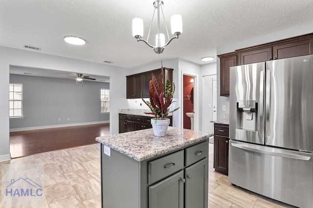 42 Kinlock Ct, Midway, GA 31320 - kitchen with stainless steel refrigerator with ice dispenser, a center island, a ceiling fan, dark brown cabinetry, and light stone counters