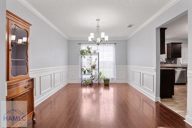 42 Kinlock Ct, Midway, GA 31320 - unfurnished dining area with a chandelier, wainscoting, wood finished floors, a textured ceiling, and a decorative wall