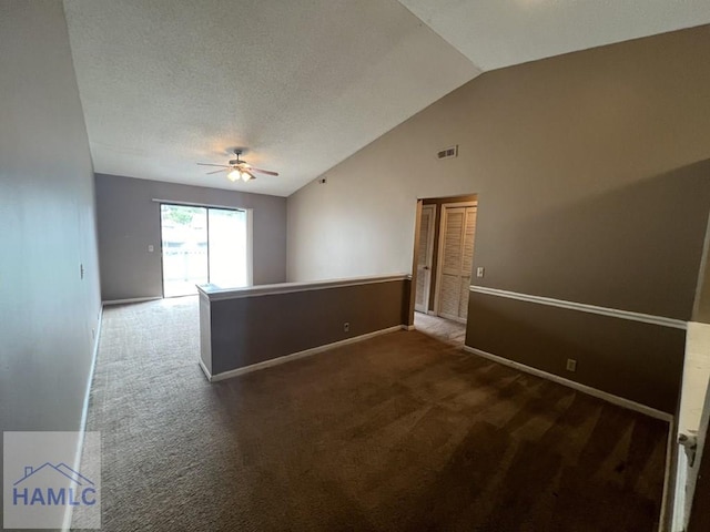 spare room featuring vaulted ceiling, ceiling fan, a textured ceiling, and dark carpet