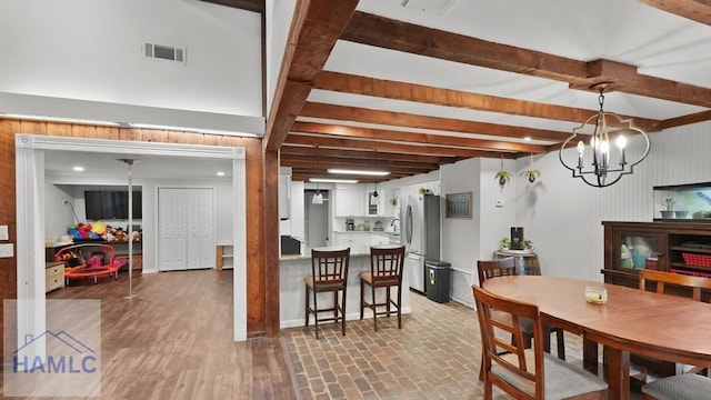 dining space featuring an inviting chandelier, beam ceiling, and hardwood / wood-style flooring