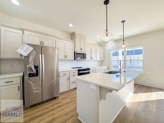 kitchen with white cabinets, appliances with stainless steel finishes, a kitchen island, and hanging light fixtures