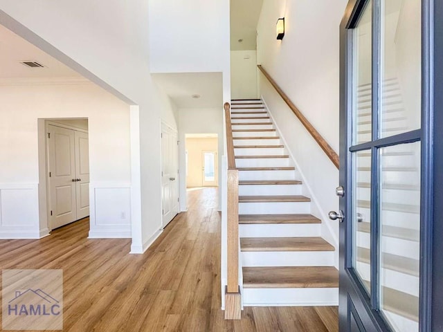 stairs featuring wood-type flooring and ornamental molding