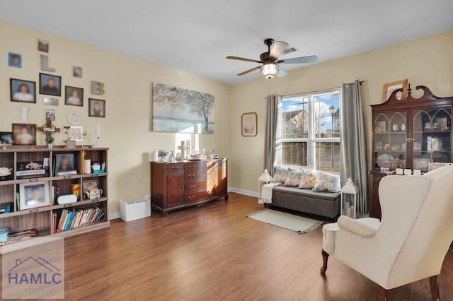 living area with ceiling fan, baseboards, and wood finished floors