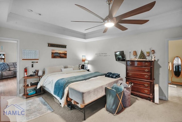 bedroom with a raised ceiling, carpet flooring, a ceiling fan, and ornamental molding