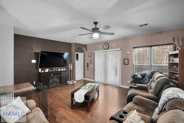 living area with visible vents, arched walkways, wood finished floors, and a ceiling fan