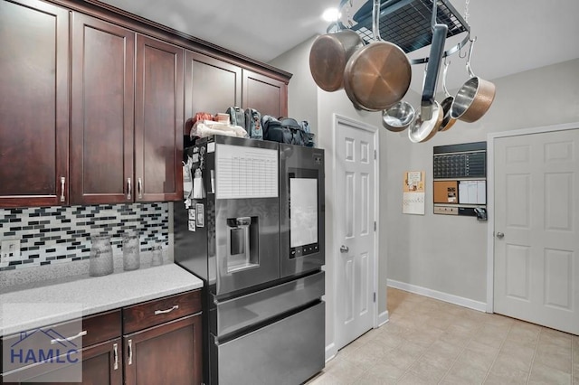 kitchen with dark brown cabinets, baseboards, stainless steel fridge, and backsplash