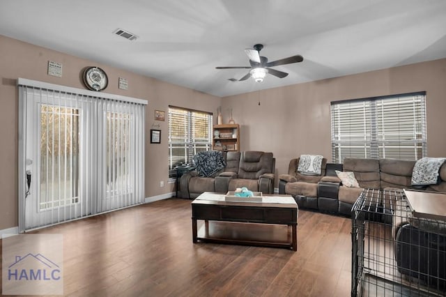 living room featuring visible vents, baseboards, ceiling fan, and wood finished floors