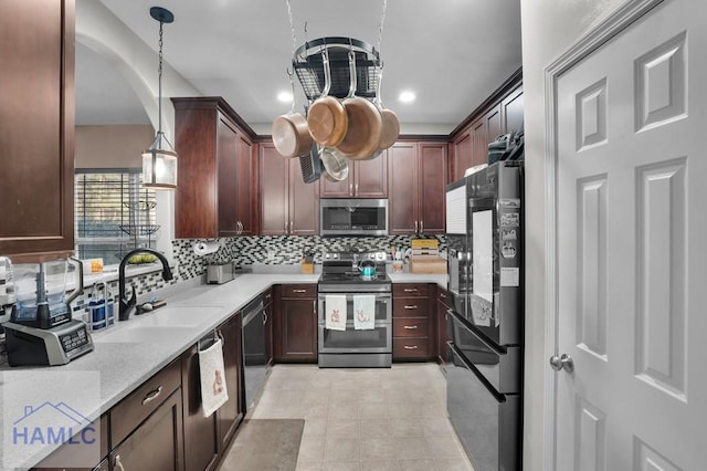 kitchen with tasteful backsplash, decorative light fixtures, appliances with stainless steel finishes, arched walkways, and a sink