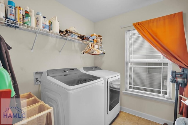 clothes washing area featuring laundry area, light tile patterned flooring, washing machine and dryer, and baseboards