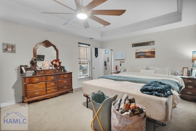 bedroom featuring light carpet, ceiling fan, baseboards, and a tray ceiling