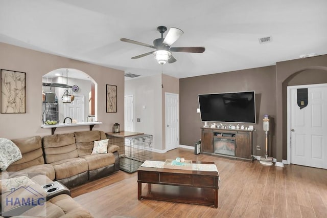 living area featuring visible vents, wood finished floors, arched walkways, baseboards, and ceiling fan