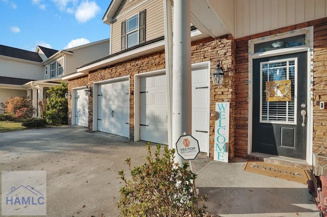 property entrance featuring a garage, stone siding, and concrete driveway