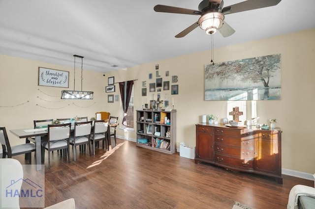 dining area featuring ceiling fan with notable chandelier, baseboards, and wood finished floors