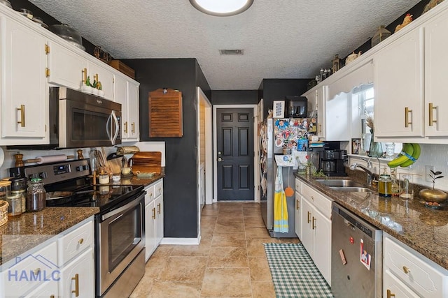 kitchen featuring white cabinets, sink, dark stone countertops, a textured ceiling, and appliances with stainless steel finishes