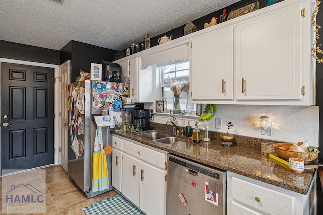 kitchen featuring white cabinetry, sink, stainless steel appliances, dark stone countertops, and a textured ceiling