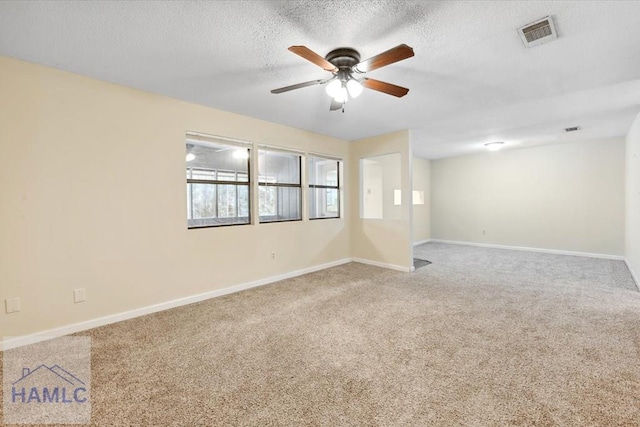 spare room with visible vents, baseboards, ceiling fan, carpet flooring, and a textured ceiling