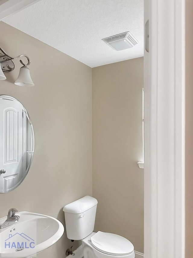 bathroom with sink, a textured ceiling, and toilet