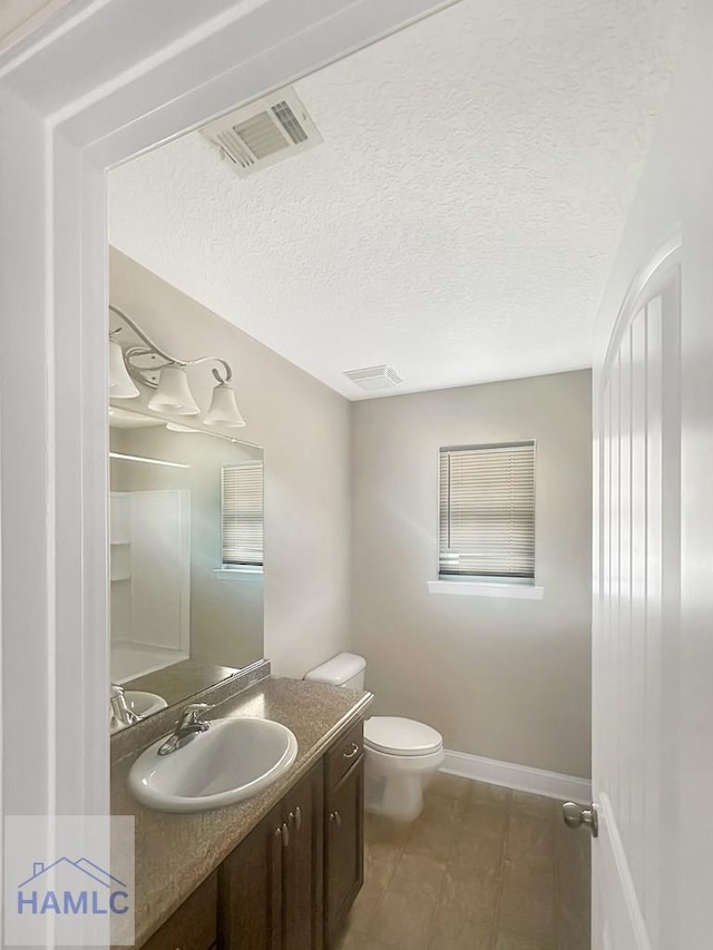 bathroom with vanity, a textured ceiling, and toilet