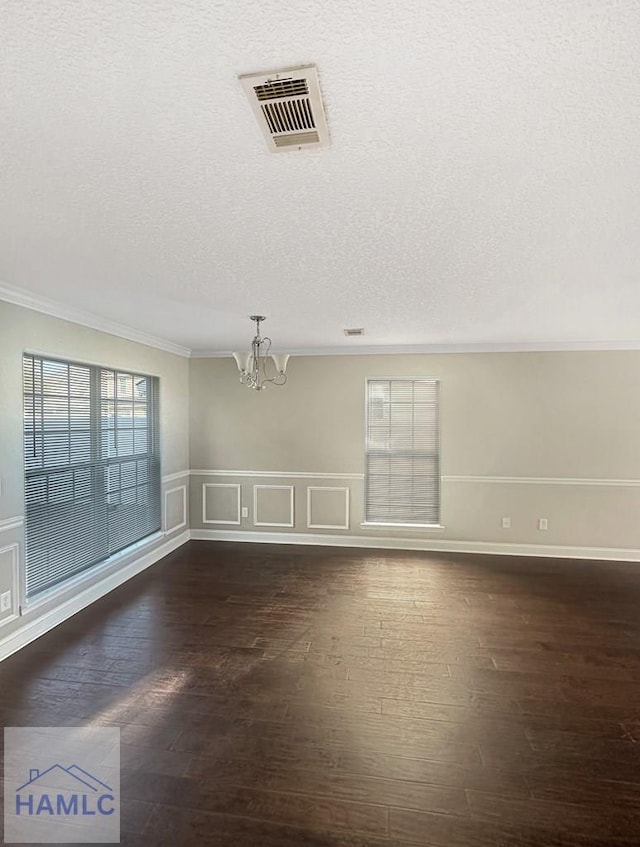 spare room with crown molding, dark hardwood / wood-style floors, a chandelier, and a textured ceiling