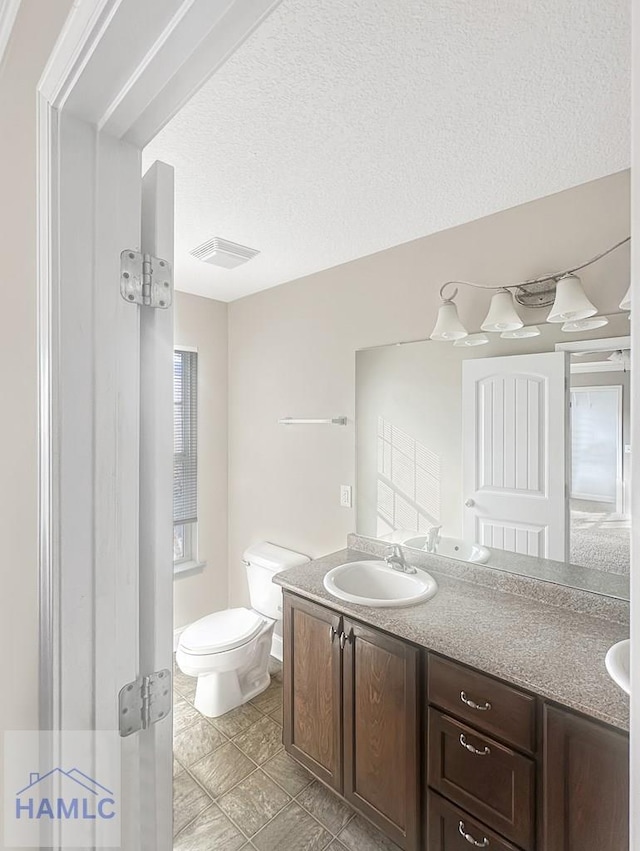 bathroom featuring vanity, a textured ceiling, and toilet