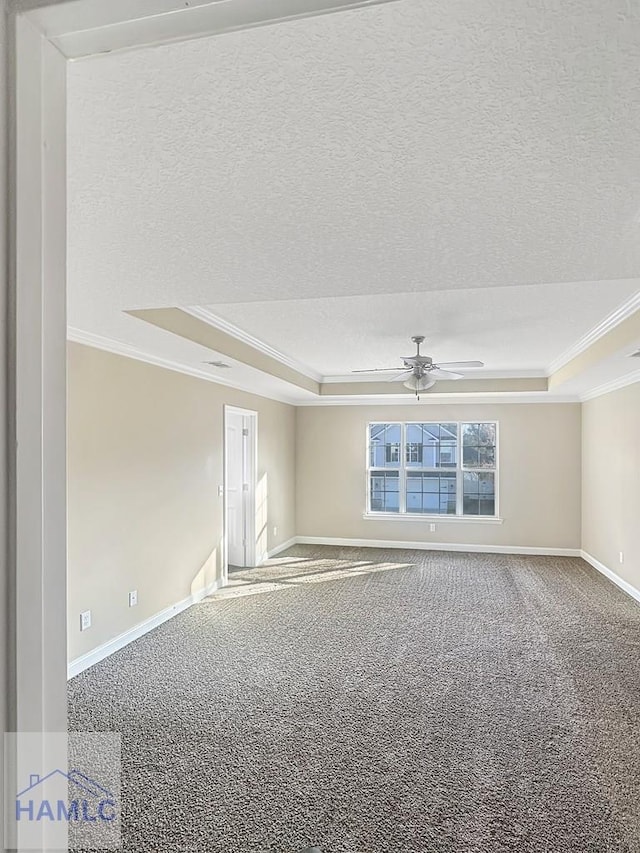 carpeted empty room featuring ceiling fan, ornamental molding, a raised ceiling, and a textured ceiling