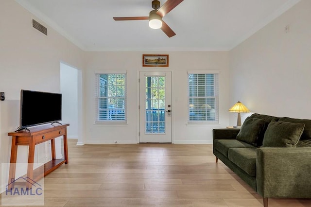 living room featuring ceiling fan, ornamental molding, and light wood-type flooring