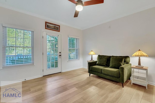 living area featuring ceiling fan, crown molding, light hardwood / wood-style flooring, and a healthy amount of sunlight