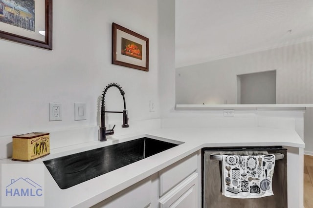 kitchen with sink, white cabinetry, dishwashing machine, kitchen peninsula, and hardwood / wood-style flooring