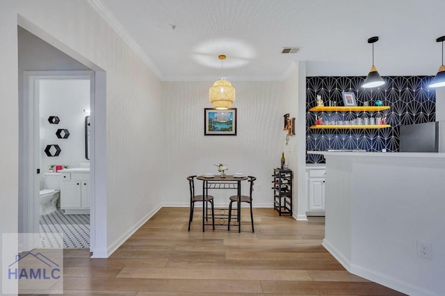 bar with white cabinetry, decorative light fixtures, ornamental molding, and light hardwood / wood-style floors