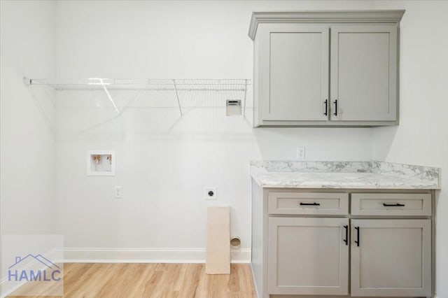 washroom featuring electric dryer hookup, cabinets, washer hookup, and light wood-type flooring