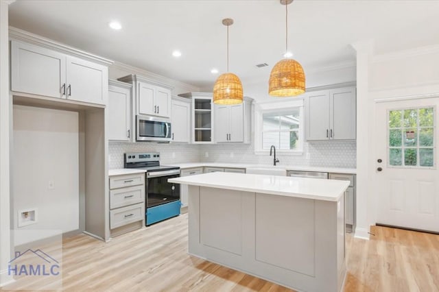 kitchen featuring sink, hanging light fixtures, stainless steel appliances, plenty of natural light, and a kitchen island