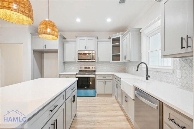 kitchen with pendant lighting, crown molding, sink, tasteful backsplash, and stainless steel appliances