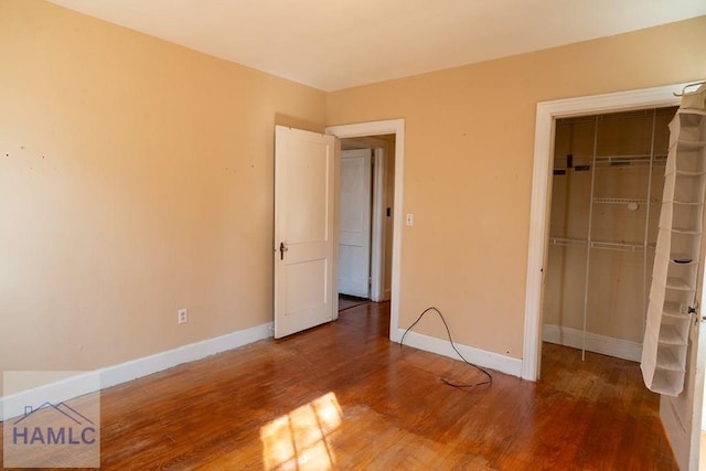 unfurnished bedroom with a closet, baseboards, and wood finished floors