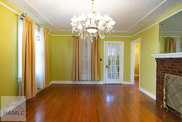 unfurnished dining area with a fireplace, ornamental molding, a textured ceiling, wood finished floors, and baseboards