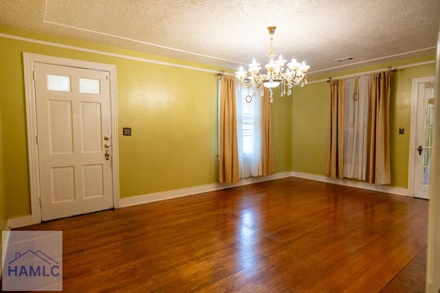 foyer entrance featuring a chandelier, a textured ceiling, wood finished floors, and baseboards