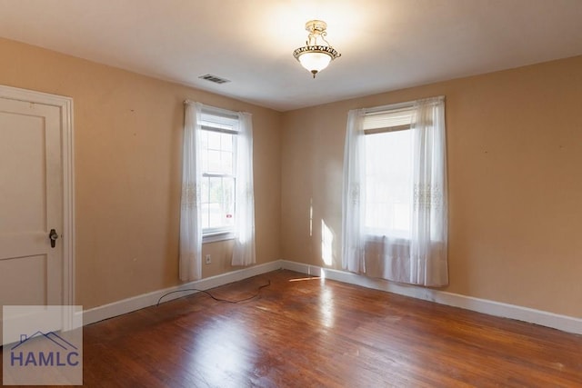 spare room featuring visible vents, baseboards, and wood finished floors