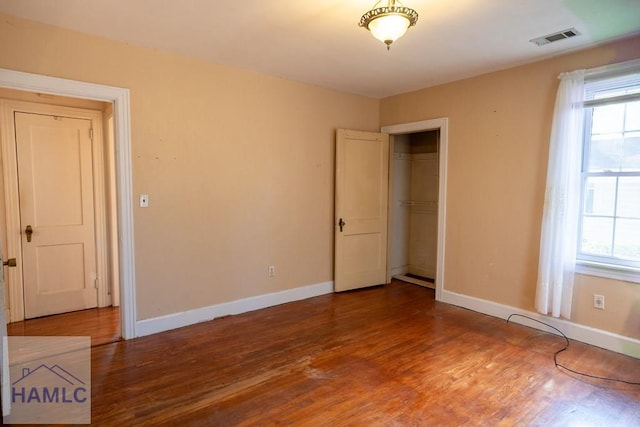 unfurnished bedroom with multiple windows, baseboards, and wood finished floors