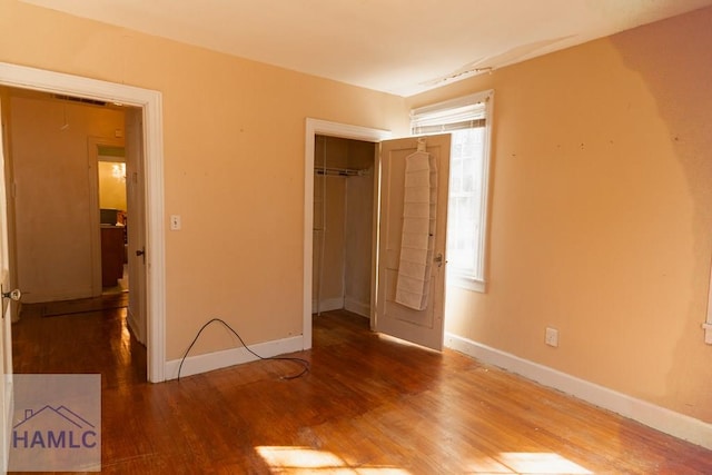 unfurnished bedroom with a closet, wood finished floors, and baseboards