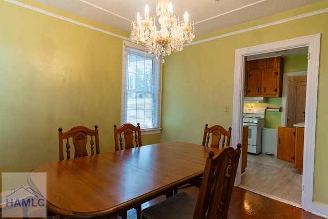 dining space with an inviting chandelier, wood finished floors, and crown molding