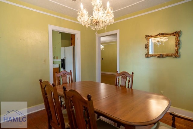 dining space featuring a chandelier, ornamental molding, baseboards, and wood finished floors