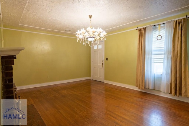 interior space featuring a textured ceiling, a chandelier, wood finished floors, baseboards, and crown molding