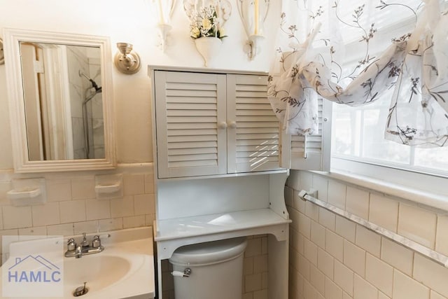 bathroom with toilet, vanity, and tile walls