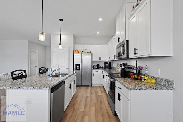 568 Abode Ave, Hinesville, GA 31313 - kitchen featuring stainless steel appliances, light wood finished floors, white cabinetry, light stone countertops, and a kitchen island with sink