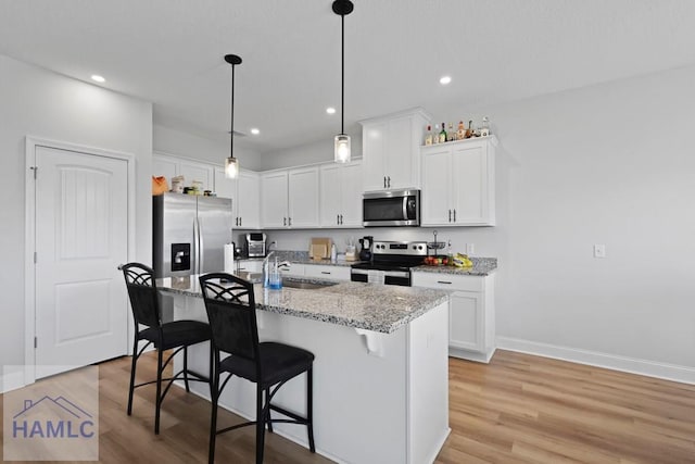 568 Abode Ave, Hinesville, GA 31313 - kitchen with appliances with stainless steel finishes, light wood finished floors, a breakfast bar area, white cabinetry, and a kitchen island with sink