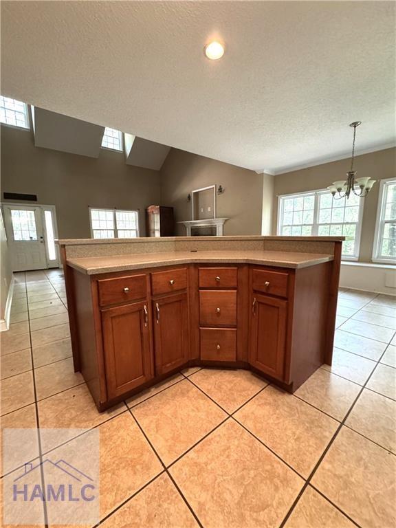 440 Arnold River Rd, Jesup, GA 31545 - kitchen with a chandelier, brown cabinetry, light countertops, a textured ceiling, and hanging light fixtures