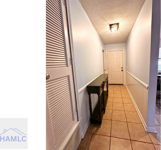 doorway with a textured ceiling and light tile patterned floors