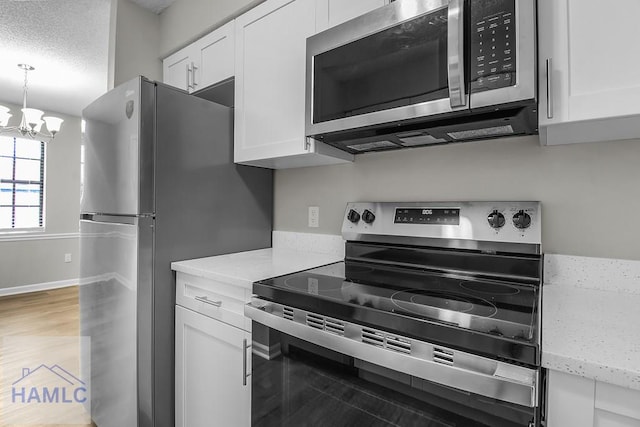 197 Sequoia Cir, Hinesville, GA 31313 - kitchen featuring light wood-style floors, a textured ceiling, white cabinets, appliances with stainless steel finishes, and a notable chandelier