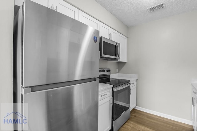 197 Sequoia Cir, Hinesville, GA 31313 - kitchen with light countertops, a textured ceiling, visible vents, stainless steel appliances, and wood finished floors